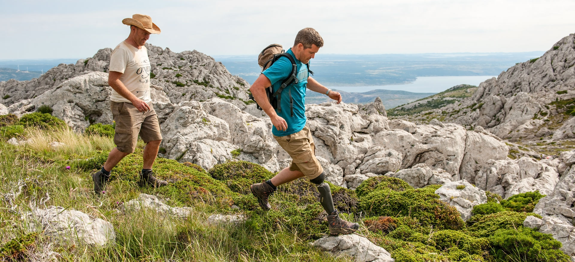 Zwei Männer wandern mit einer Beinprothese den Berg entlang